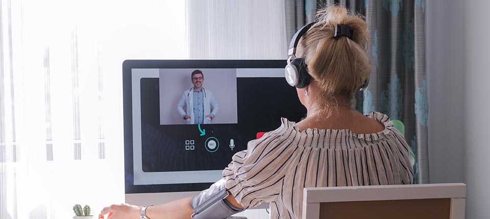 Woman blood pressure and consulting with her doctor online on her computer.